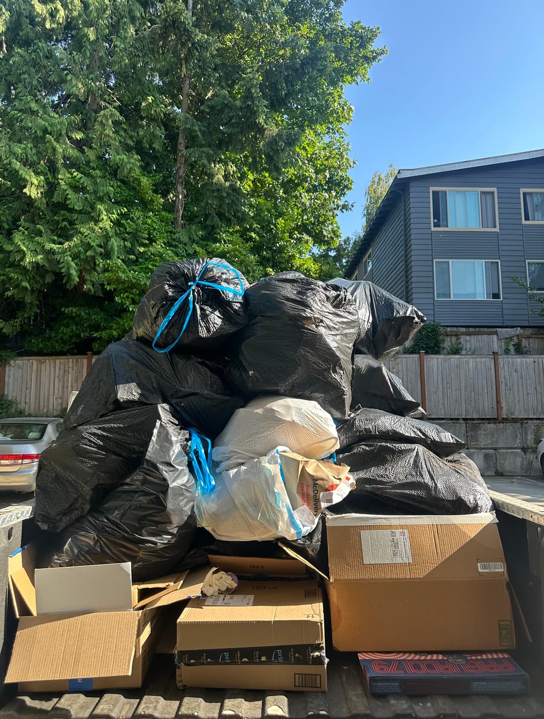 Truck bed piled with bagged trash and cardboard boxes from an apartment junk removal