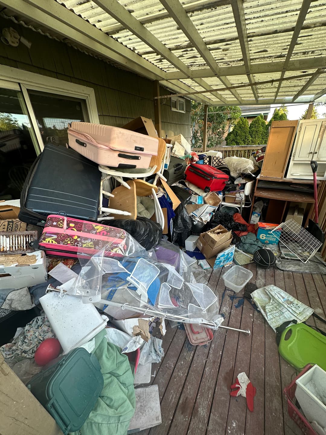 Cluttered back deck full of luggage, furniture, and household items before a junk removal cleanout