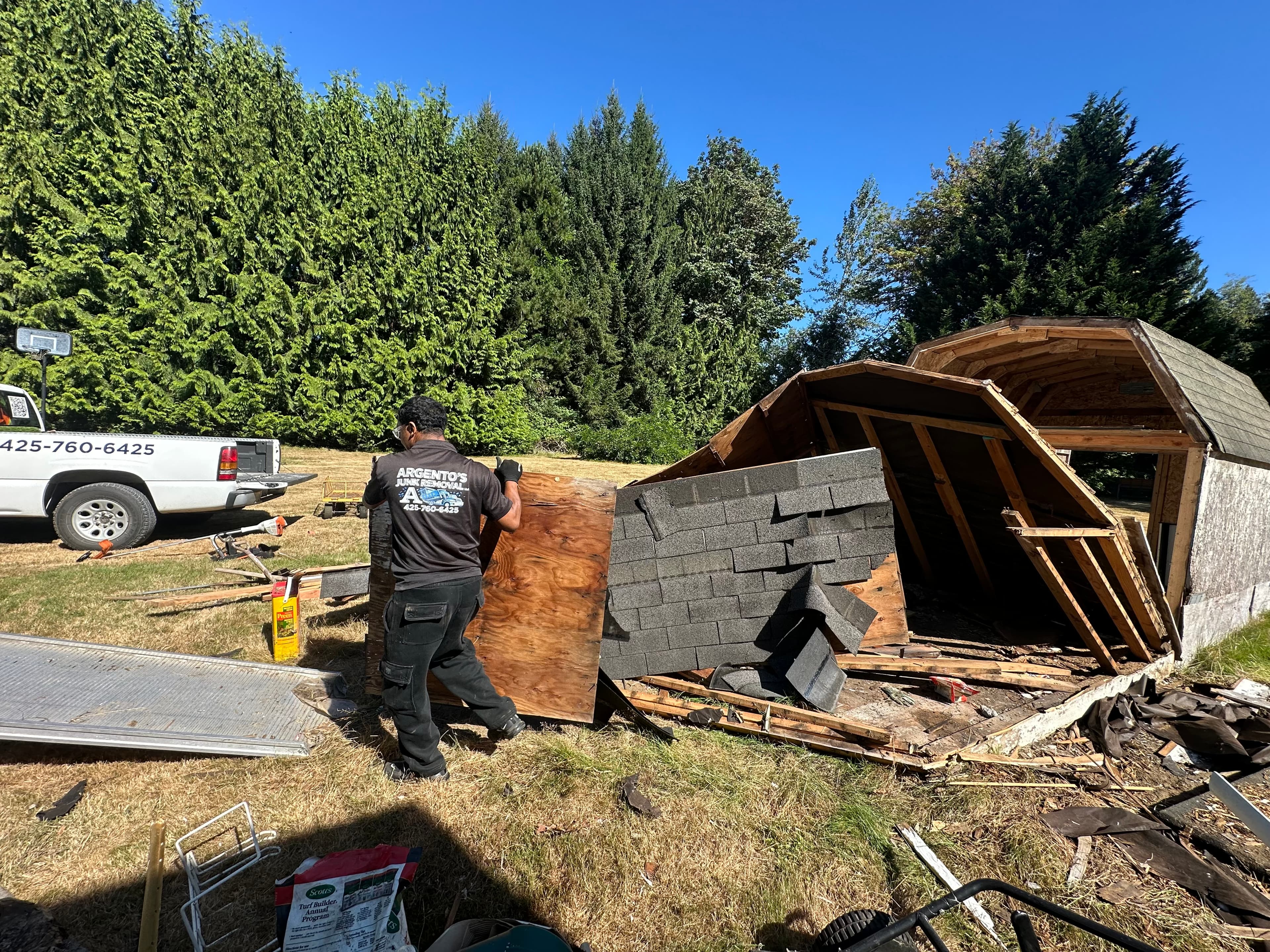 Argento’s Junk Removal crew member hauling debris during a shed teardown project