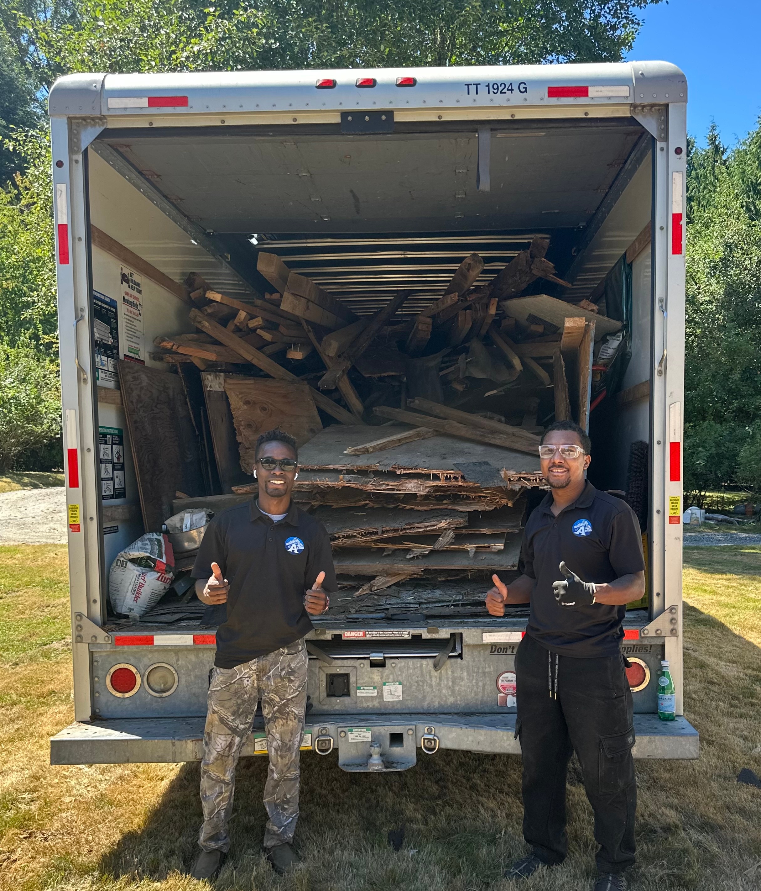 Argento’s Junk Removal Service crew giving a thumbs up in front of a loaded junk removal truck
